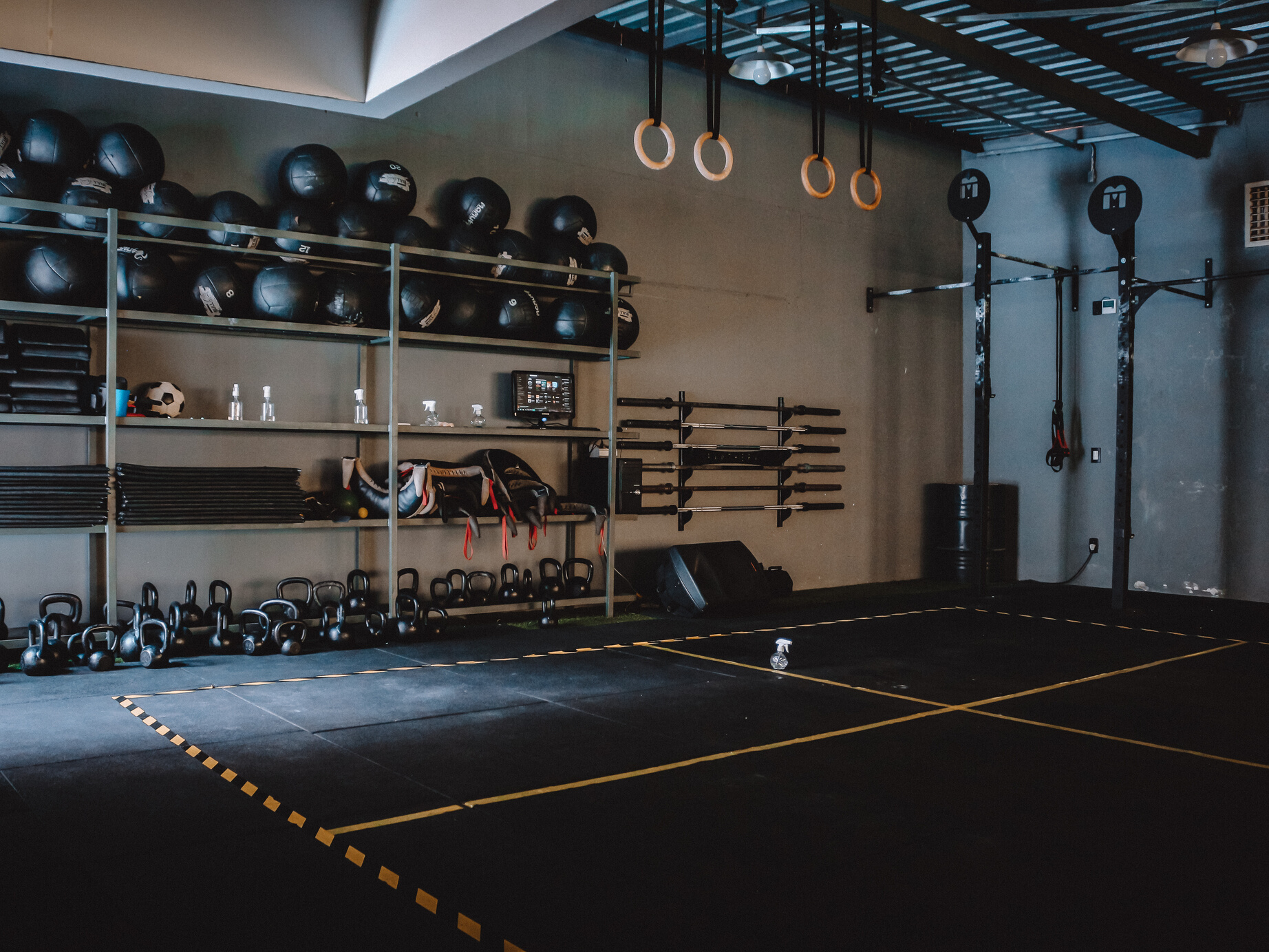 A CrossFit Box with Equipment on a Steel Shelves Near a Gymnastic Rings 